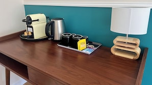 A wooden desk with a coffee maker, a kettle, cups, and a tray with coffee pods and a card. - Guesthouse close to Disney (Montevrain)