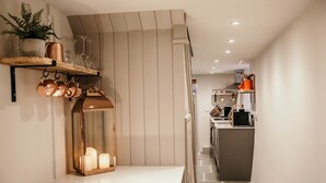 Een moderne keuken met een houten plank waarop keukengerei en een spiegel staan.