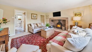 Un salon chaleureux avec une cheminée, un canapé, une table basse et un tapis rouge à motifs.