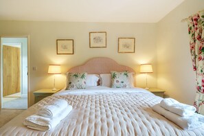 A neatly made bed with a fluffy white duvet, two bedside lamps, and floral-patterned pillows. - Cosy Cottage - Chebbard, Dorchester (Dorchester)