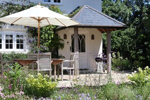 A gazebo with a wooden roof, surrounded by a garden with various flowers and a table with chairs. - Cosy Cottage - Chebbard, Dorchester (Dorchester)