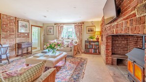 A cozy living room with a fireplace, a sofa, a coffee table, and a bookshelf.