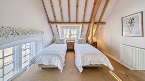 Un dormitorio con dos camas, vigas de madera, un ventanal y un radiador.