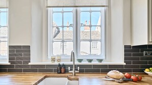 Una cocina con mostrador de madera, un lavamanos y una ventana con vistas a edificios.