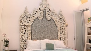 A bedroom with a large bed, ornate headboard, and a patterned bedspread.