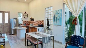 A modern kitchen with a dining area, a large window with curtains, and a view of the outdoors.