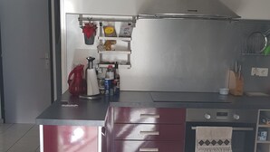A modern kitchen with a stainless steel range hood, a built-in oven, and a large island with drawers.