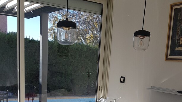 A modern kitchen with a large window, a dining table with chairs, and a view of a swimming pool.