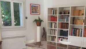 A modern library with a glass table and white chairs, surrounded by bookshelves filled with books.