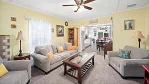 A living room with a ceiling fan, two sofas, a coffee table, and a kitchen visible through an open door. - Peaceful home in downtown CDA, 4 bed/2 bath!  Enjoy the sun on the private deck! (Coeur d'Alene)