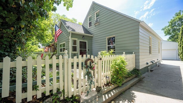A two-story house with a white picket fence, an American flag, and a garage. - Peaceful home in downtown CDA, 4 bed/2 bath!  Enjoy the sun on the private deck! (Coeur d'Alene)