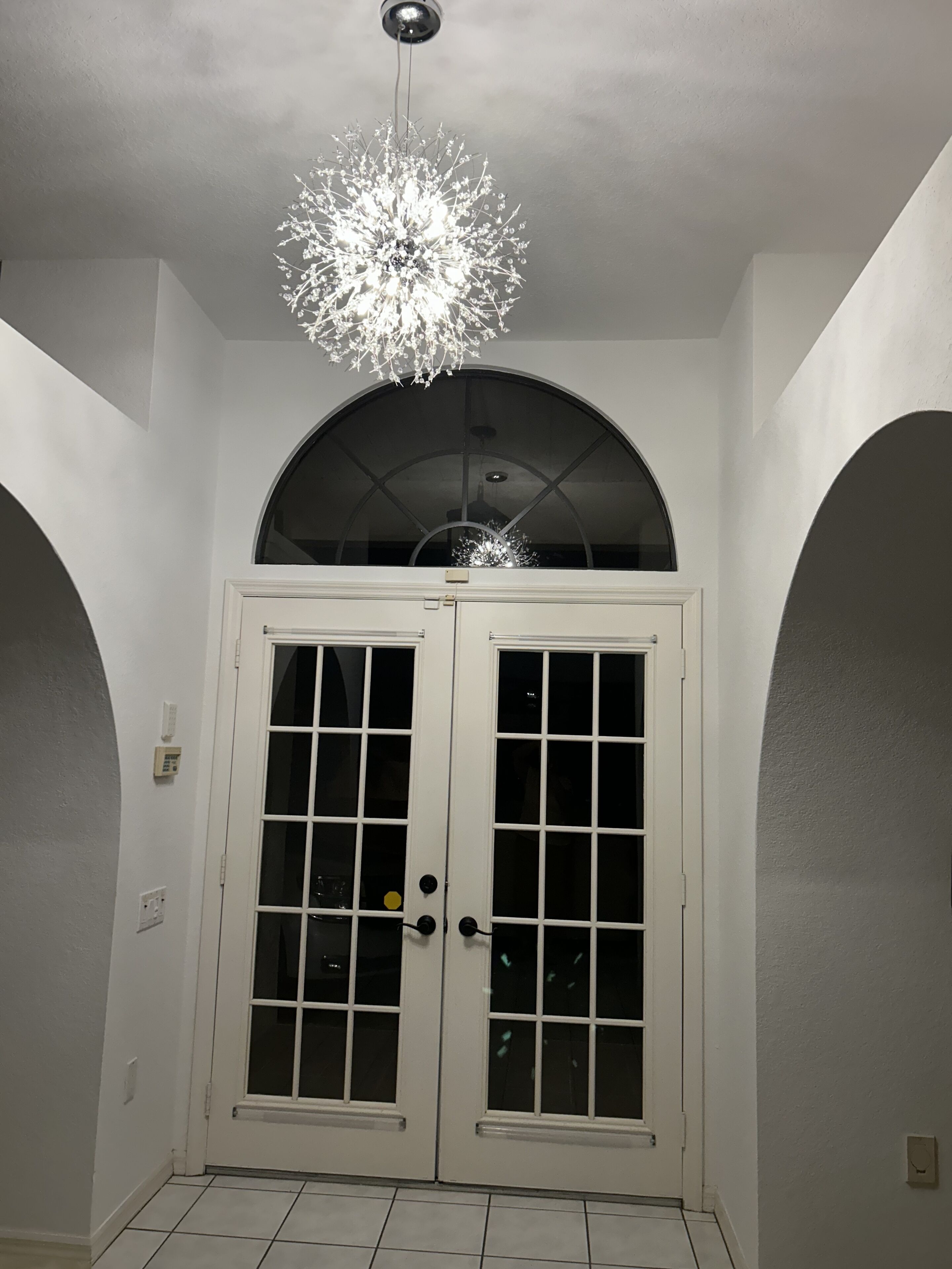 A white door with glass panels and a decorative ceiling light fixture.