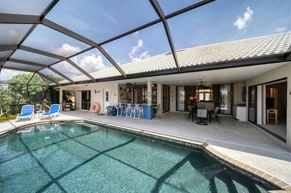 A swimming pool with a glass ceiling, bar area, and outdoor seating. - RUM CAY GETAWAY: South facing waterfront home, private pool/spa, bar, and dock. (Punta Gorda)