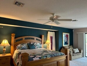 A bedroom with a bed, two bedside lamps, a ceiling fan, a chair, and a window with curtains. - RUM CAY GETAWAY: South facing waterfront home, private pool/spa, bar, and dock. (Punta Gorda)