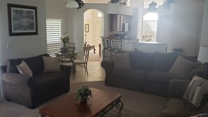 Uma sala de estar com dois sofás, uma mesa de centro e uma área de jantar com cadeiras e uma mesa.