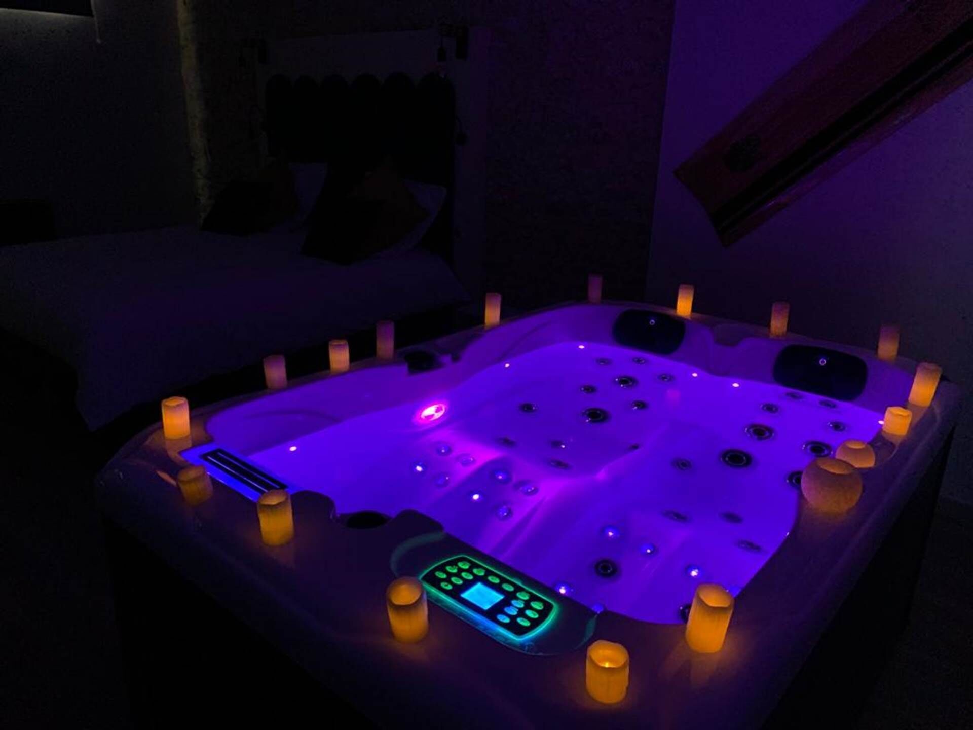 A hot tub with a control panel and multiple candles around it.