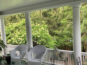 A covered porch with two wicker chairs, a small table, and a lantern.