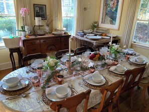A dining table set for a meal with multiple chairs, a decorative centerpiece, and a view of the outdoors.