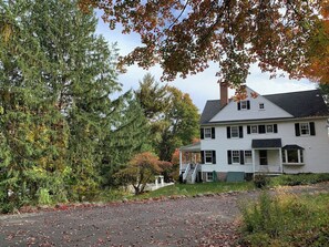 A two-story house with a porch, surrounded by trees and a driveway.