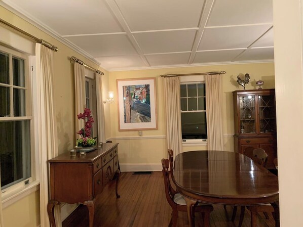 A dining room with a wooden table and chairs, a cabinet, and a painting on the wall.