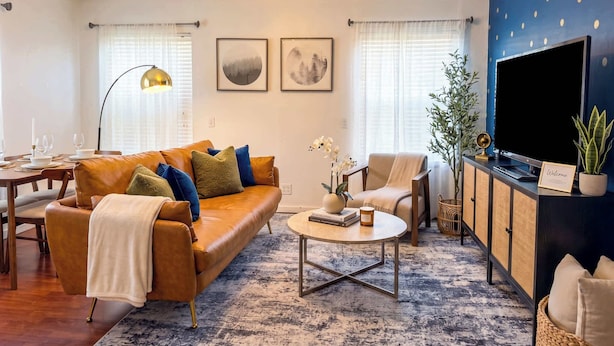 A living room with a sofa, armchairs, a coffee table, a TV, and a bookshelf.