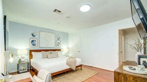 A bedroom with a bed, bedside tables, a desk, and a chair.