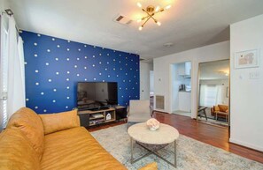 Relax in this stylish living room with a large flat-screen TV, comfortable sofa, and a beautiful vase of flowers.