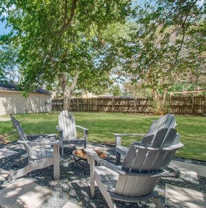 Relax by the fire pit surrounded by a tree's shade and a gravel area.