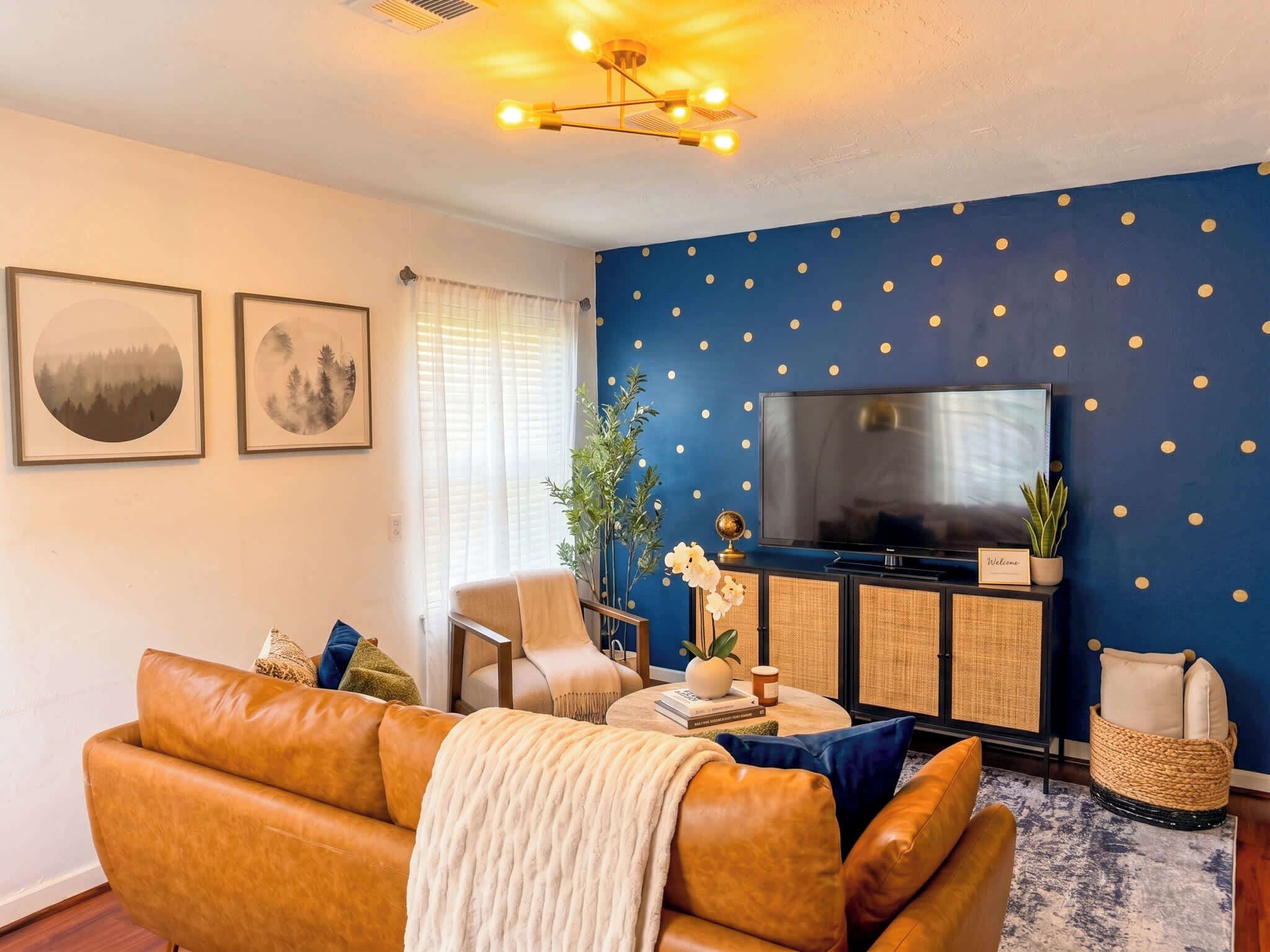 Ein Wohnzimmer mit einer Couch, einem Fernseher, einem Couchtisch und einer blauen Wand mit Punkten.