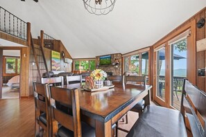 Uma sala de jantar espaçosa com uma mesa de madeira, cadeiras e um objeto decorativo central.