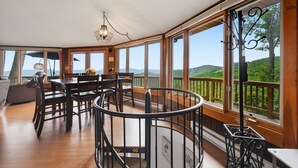 A spacious room with a dining area, large windows, and a view of the outdoors.