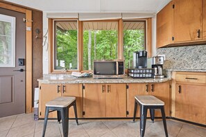 A kitchen with wooden cabinets, a microwave, a coffee maker, and a window with a view of trees. - Spectacular Views - 4 bedrooms, Sleeps 9 (Beech Mountain)