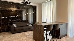 Een moderne keuken met een marmeren spatwand, een donkere bank en een eethoek met barstoelen.