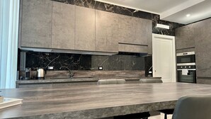 Een moderne keuken met donkere aanrechtbladen, een ingebouwde kookplaat en een groot kookeiland met zitplaatsen.