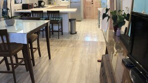 Una cocina moderna con comedor, sillas de madera, televisor y ventilador de techo.