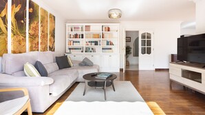 A living room with a sofa, coffee table, bookshelf, and TV.