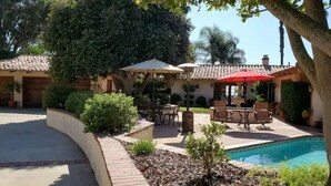Ein Patio mit Sitzgelegenheiten im Freien, einem Pool und einem Gebäude mit Ziegeldach.