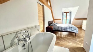 Ein modernes Schlafzimmer mit großem Fenster, Holzboden und kariertem Bettbezug.