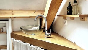 Ein modernes Badezimmer mit einem Waschbecken aus Glas, Holzregalen und einem Fenster darüber.