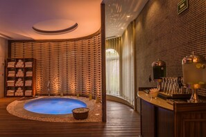 Relax in a serene spa area with a hot tub, pebble bed, and wooden bench.