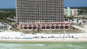 Un hotel moderno con diversi piani, situato sulla spiaggia e dotato di un parcheggio.