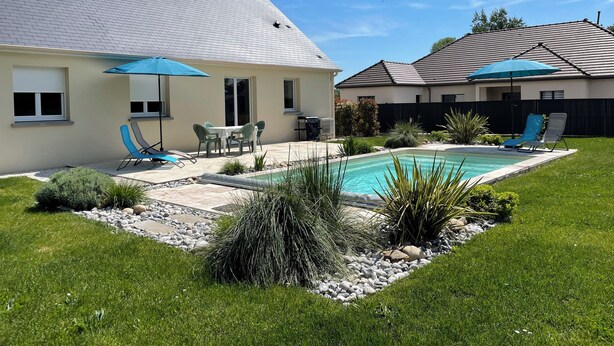 A backyard with a swimming pool, patio furniture, and a covered outdoor seating area. - Gîte les Coquelicots (Garennes-sur-Eure)