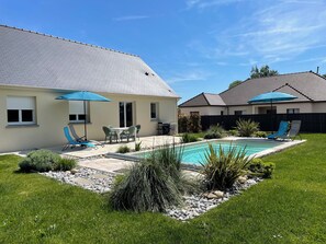 Ein Garten mit Swimmingpool, Terrassenmöbeln und einer überdachten Sitzgelegenheit.