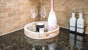 Ein Tablett mit einer Flasche Veuve du Vernay Eiswein, zwei leere Weingläser, einer Kerze und zwei Flaschen Öl und Essig auf einer Granitabdeckung.
