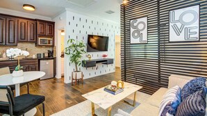 Eine moderne Küche mit dunklen Holzschränken, einer integrierten Mikrowelle und einem Essbereich mit weißem Tisch und schwarzen Stühlen.