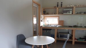 A compact kitchen with a dining area, featuring a round table, two chairs, a microwave, and a toaster. - Cabin near Frutillar Lake Llanquihue (Casma)