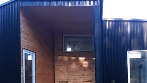 A small wooden cabin with a sliding glass door, two chairs, a blue bucket, and a small dog. - Cabin near Frutillar Lake Llanquihue (Casma)