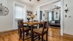A dining area with a wooden table and chairs, a ceiling fan, and a view into a living room with a sofa and curtains. - Check It Out! Great Location Large Priv w/Parking (Dubuque)