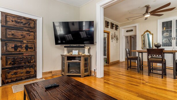 A living room with a wooden floor, a TV on a stand, a dining table with chairs, and a ceiling fan. - Check It Out! Great Location Large Priv w/Parking (Dubuque)