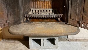 Una chimenea rústica con repisa de madera y rejilla de metal.